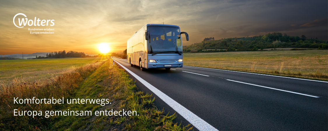 Ein Reisebus fährt auf einer Landstraße in einen goldenen Sonnenuntergang. Text: „Komfortabel unterwegs. Europa gemeinsam entdecken.“ Logo: Wolters.